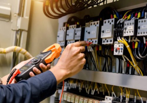 Electrician engineer work  tester measuring  voltage and current of power electric line in electical cabinet control.